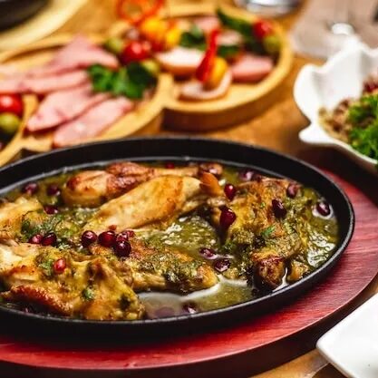 portugal-food-side-view-stewed-chicken-with-onion-greens-pomegranate-clay-dish